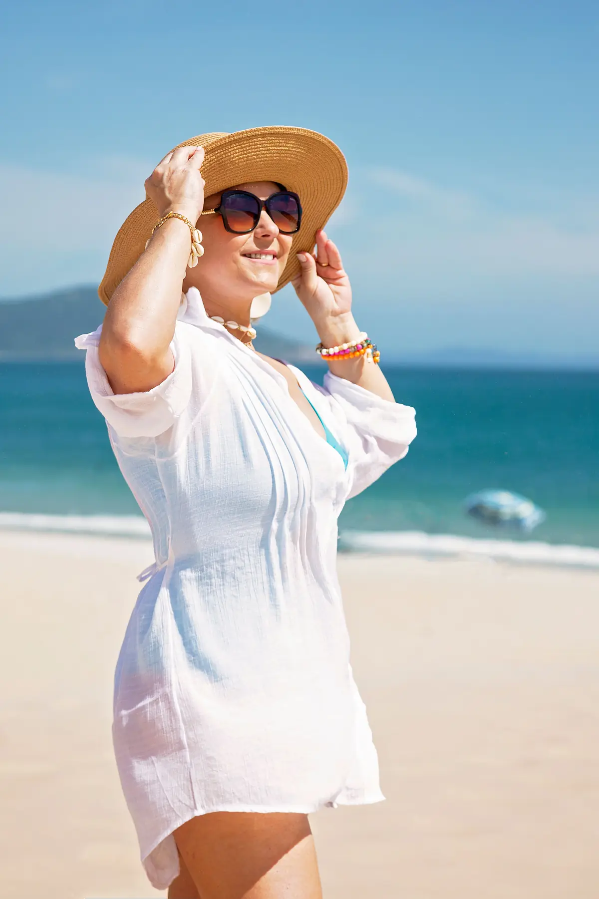 Illustrative stock photograph of a mature female model wearing a hat by the coast